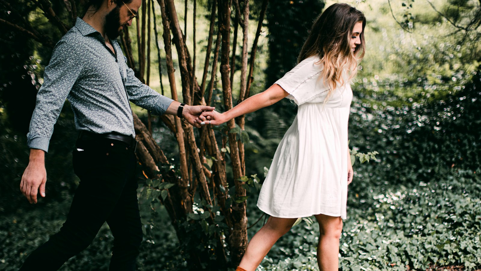 A couple holding hands while stepping across natural stone steps in a garden