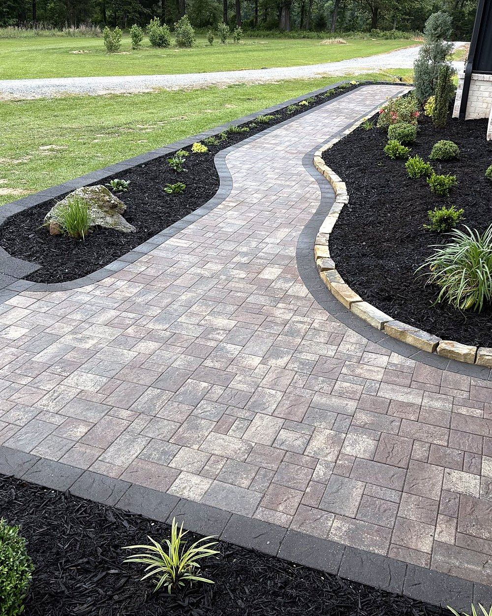 A curved paver walkway with a charcoal border between new planting beds, built by Amanda's Villa