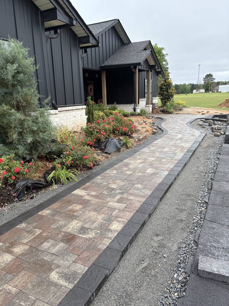 A long paver walkway with a charcoal border running between new planting beds