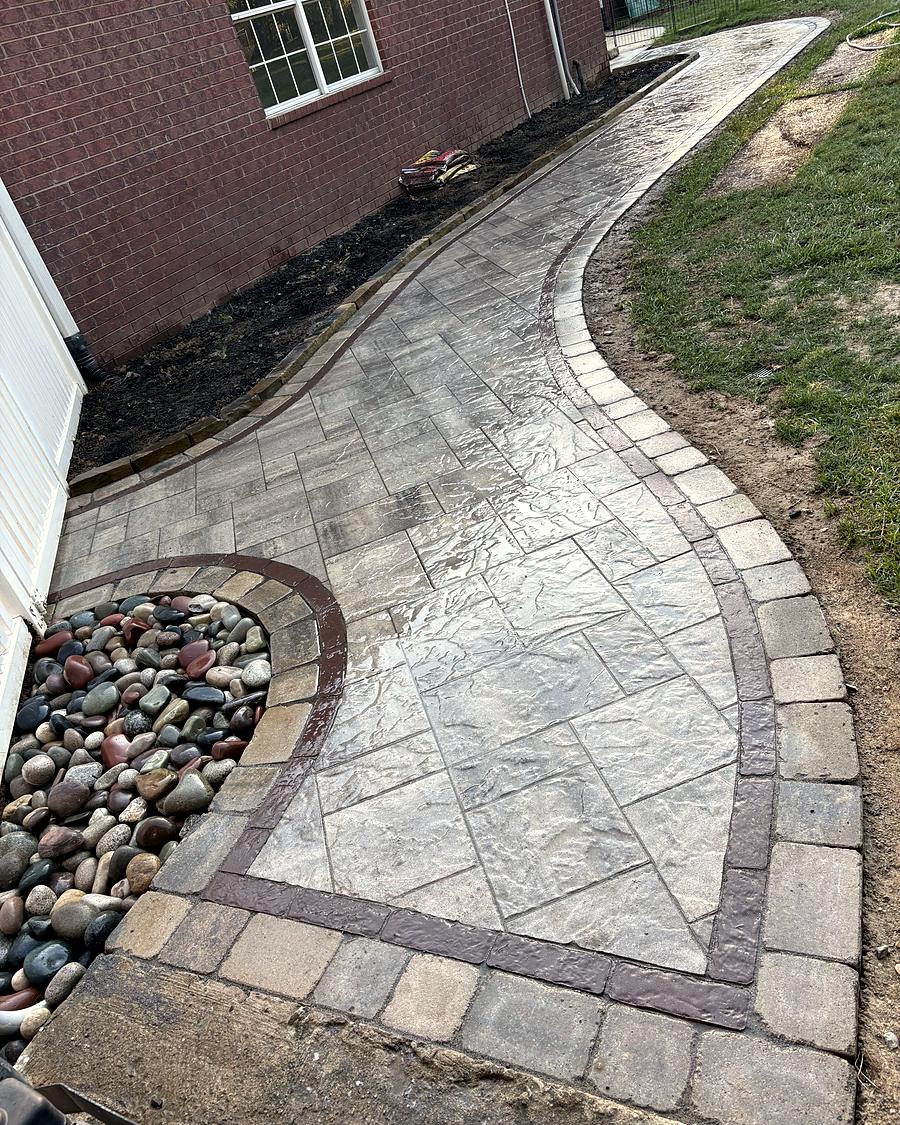 A paver walkway bending around a river rock bed, built by Amanda's Villa
