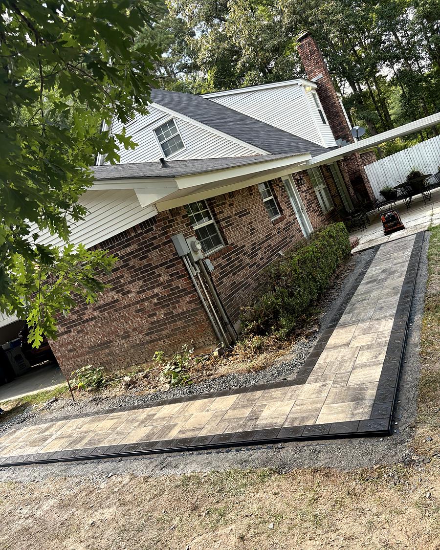 A paver path wrapping the corner of a brick house, built by Amanda's Villa