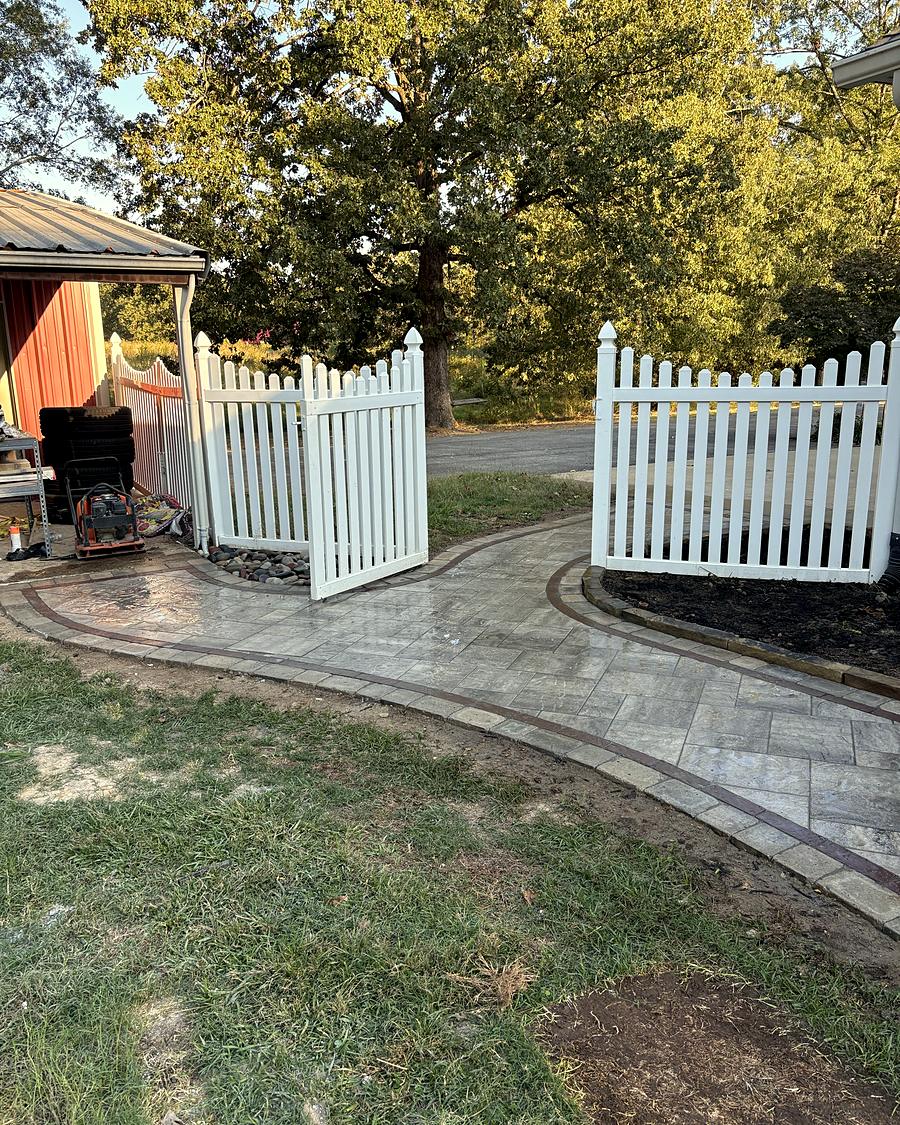 A curved paver walkway through a white picket gate, built by Amanda's Villa