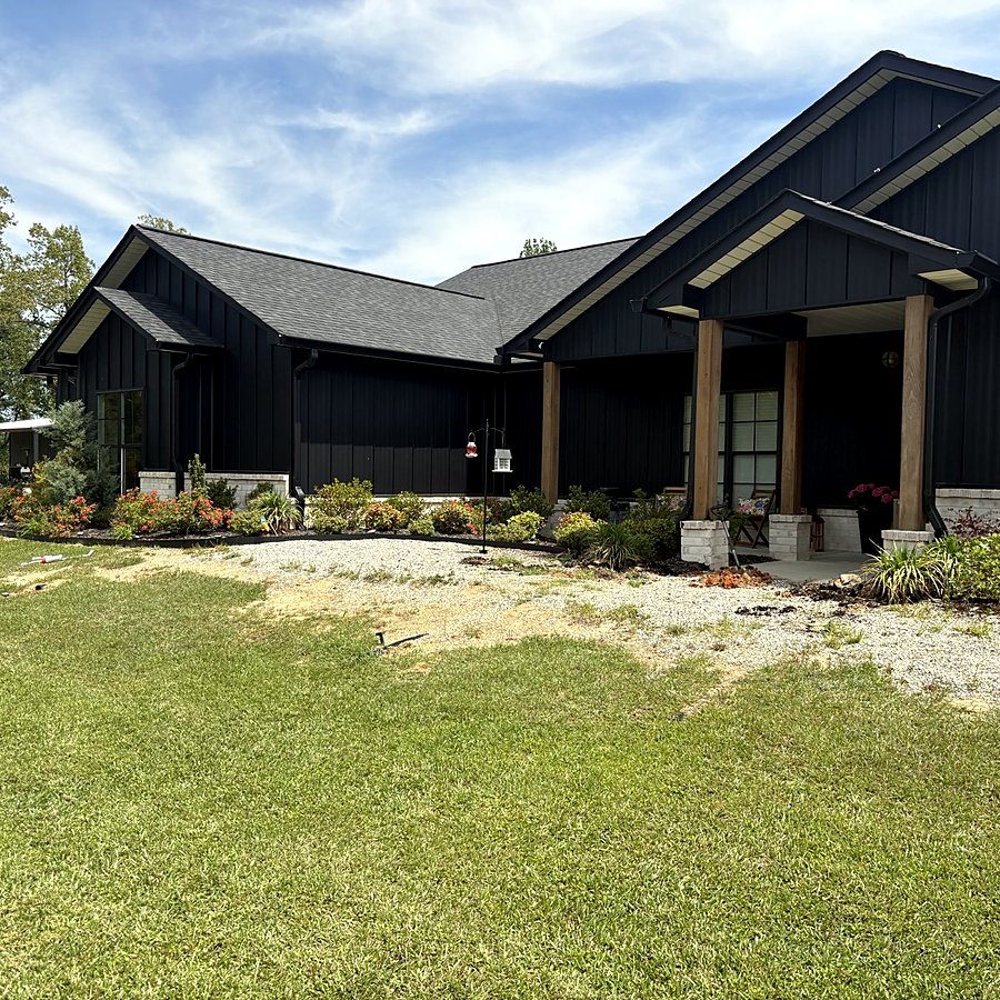 A front yard beside a black farmhouse before a hardscape project
