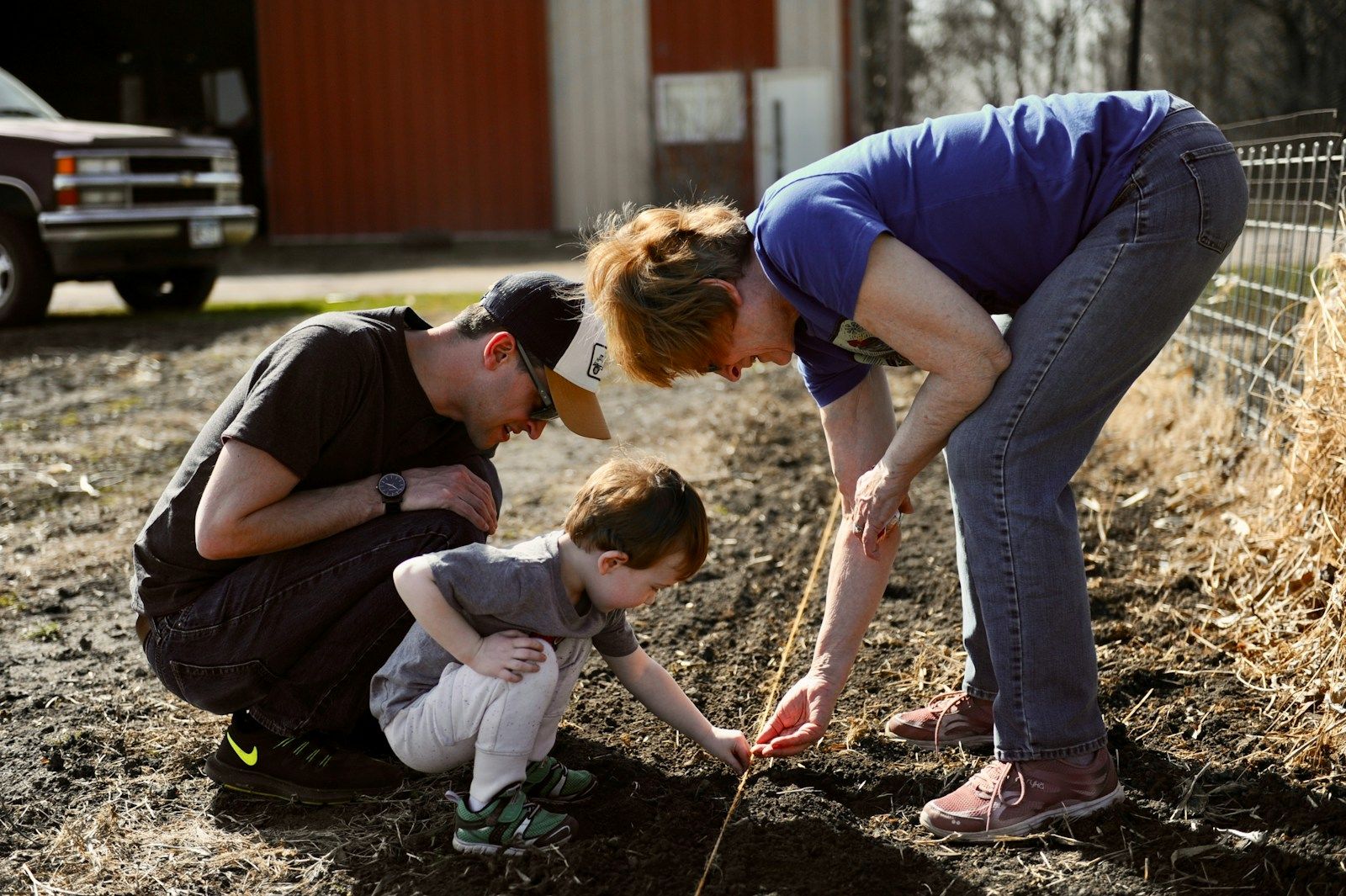 A mother, father and young son planting together in freshly turned garden soil