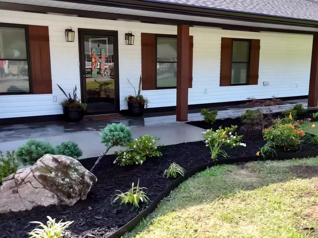 After: A long bed of shrubs, perennials and a feature boulder along the porch.