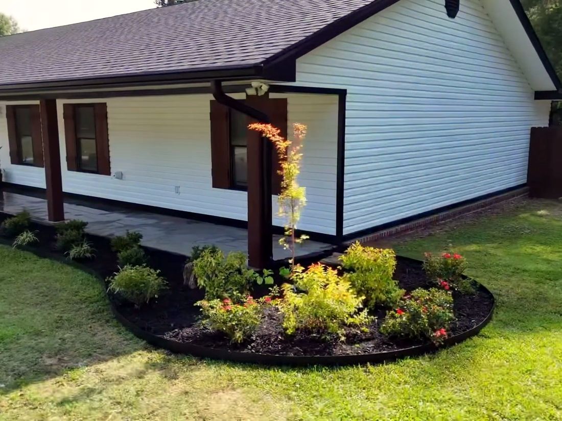 After: A curved mulched bed with a Japanese maple and flowering shrubs at the porch corner.