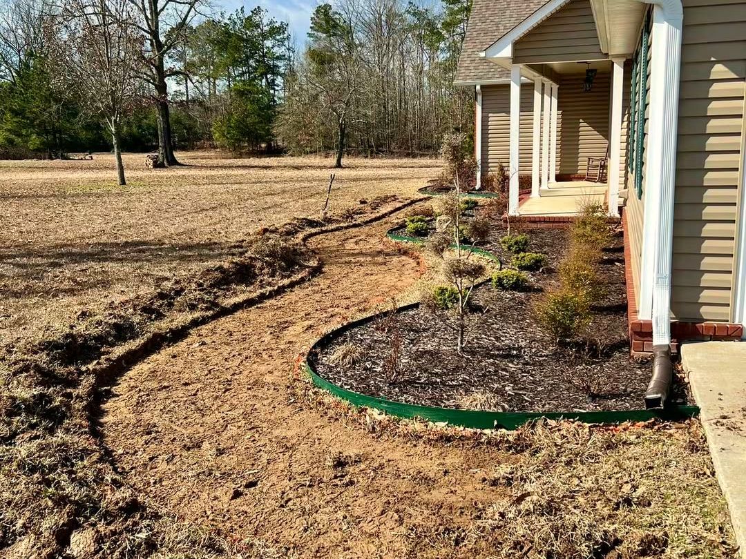 Before: A bed outline dug into bare ground beside a house