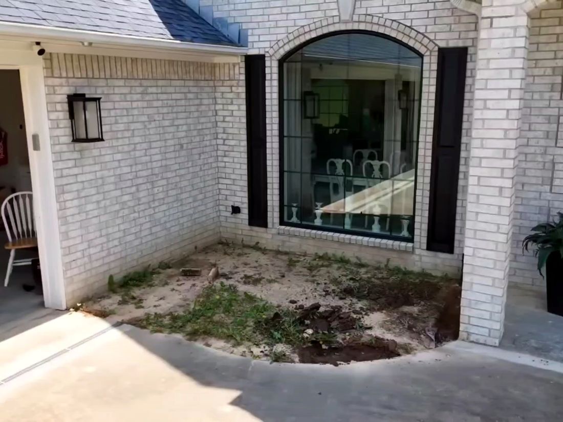 Before: Bare sand and weeds in a corner by the garage