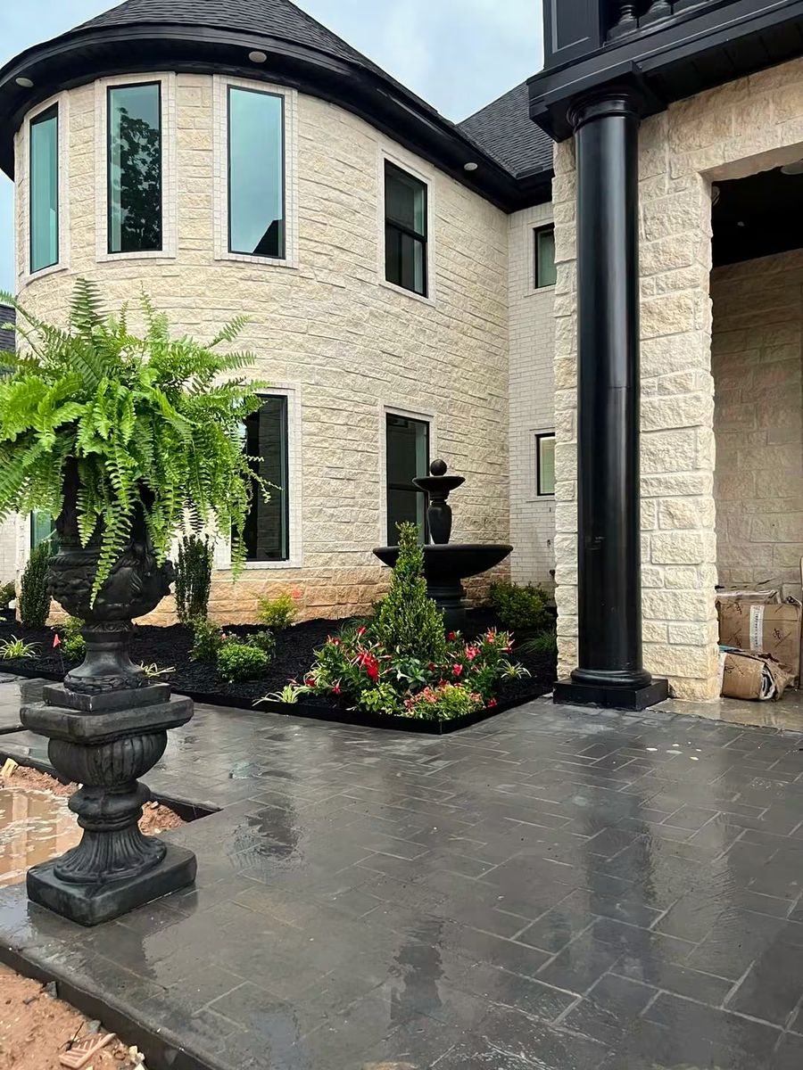 A Boston fern in a tall black urn beside a front door, planted by Amanda's Villa