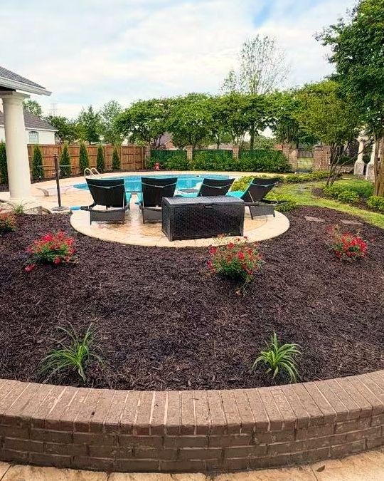 A raised circular bed with a brick wall around a backyard seating area