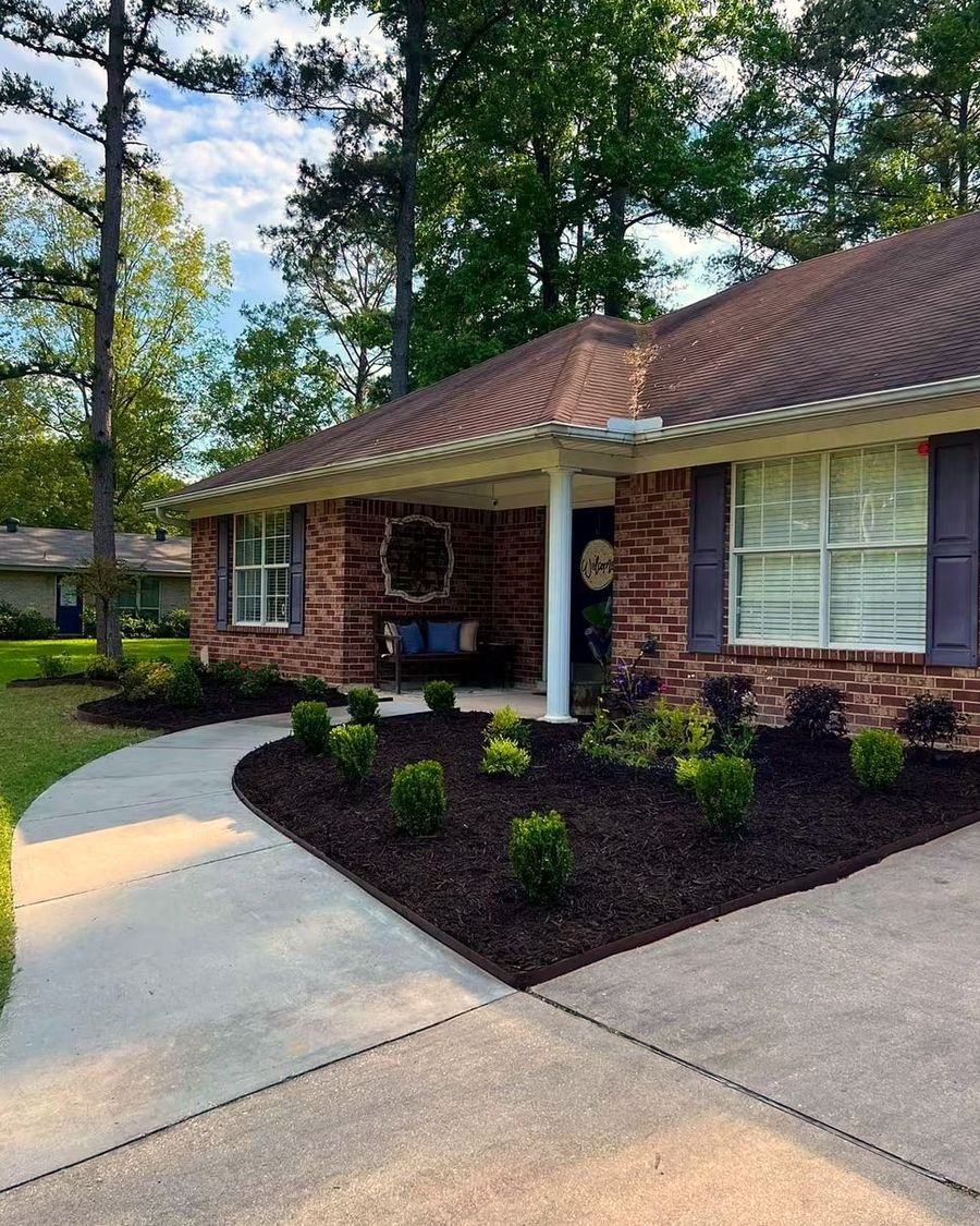 A curved bed of boxwoods along the front walk of a brick ranch house, landscaped by Amanda's Villa