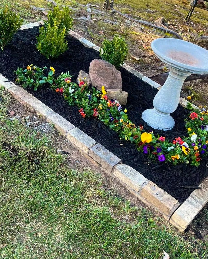 A bird bath in an edged flower bed, planted by Amanda's Villa