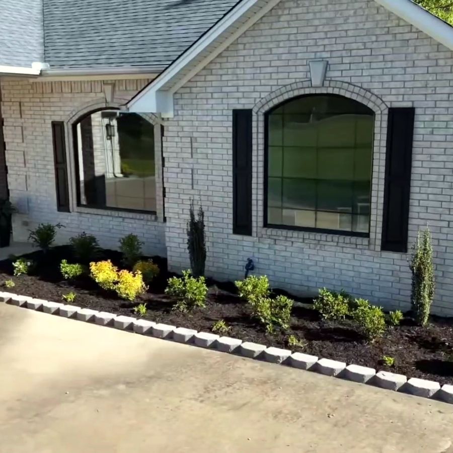 The same corner finished with a mulched bed of shrubs and a stone block border
