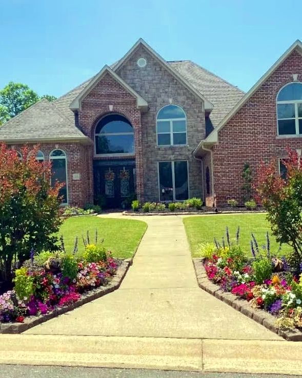 A front walk lined with new flower beds leading to a brick house, landscaped by Amanda's Villa