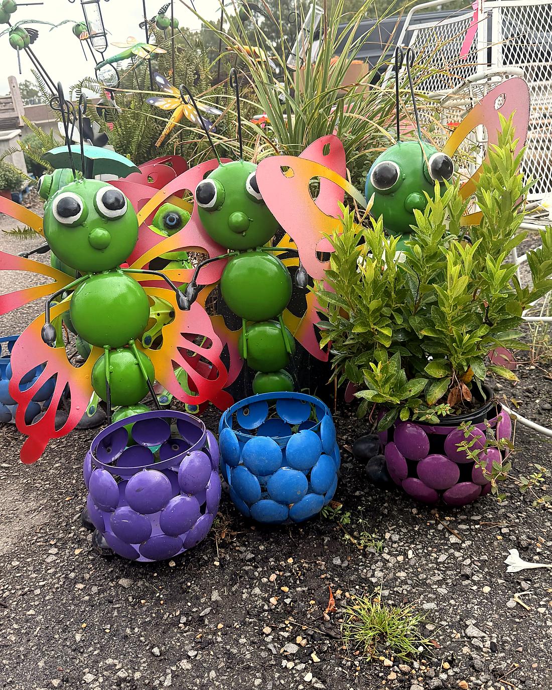 Painted metal frog garden ornaments beside purple and blue ceramic planters at Amanda's Villa Garden Center