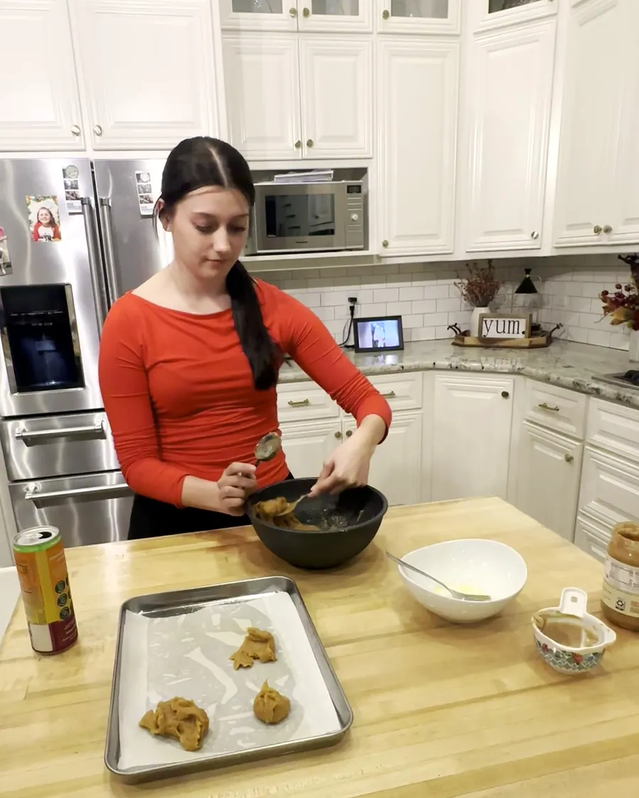 Anna Kate shaping peanut butter cookie dough onto a parchment-lined tray