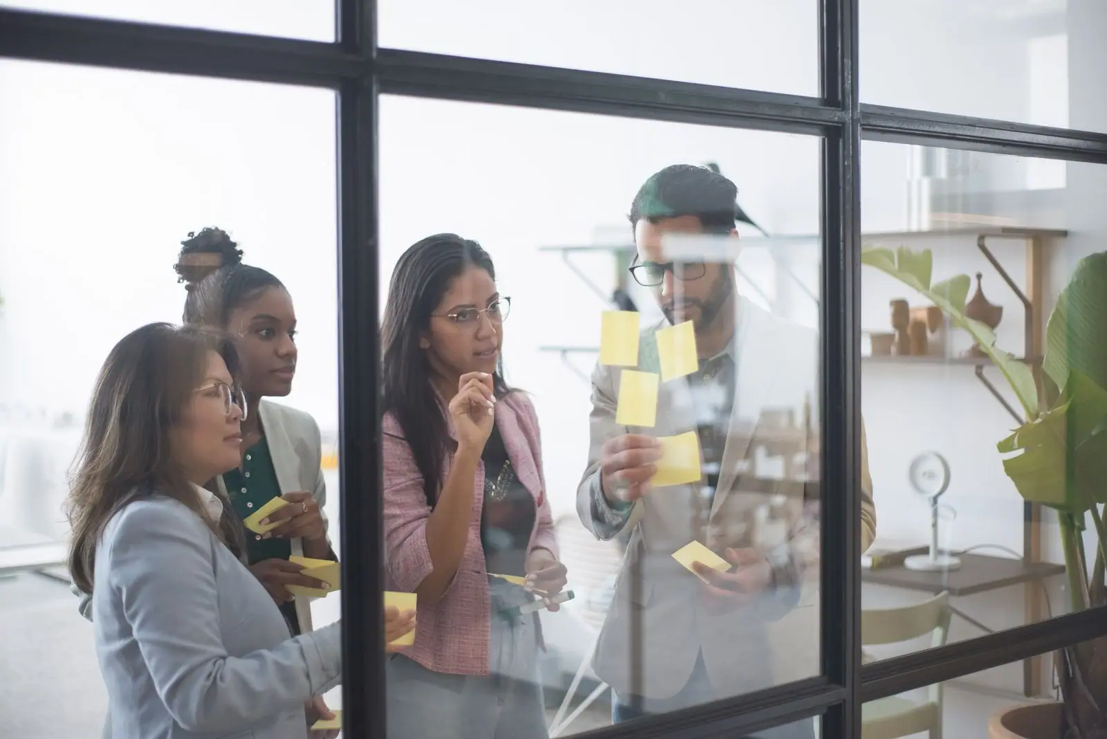 A team working through sticky notes on a glass wall